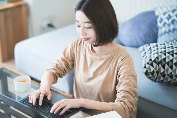 Asian blogger blogging  on a coffee table about her travels.